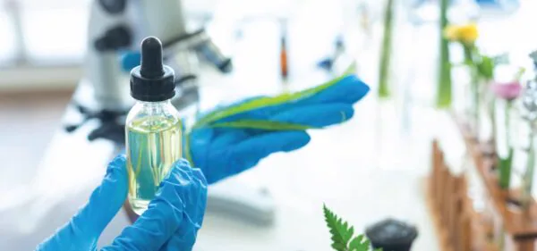 Gloved laboratory technician holding a dropper bottle