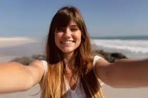 Beautiful young woman looking at camera on beach in the sunshine